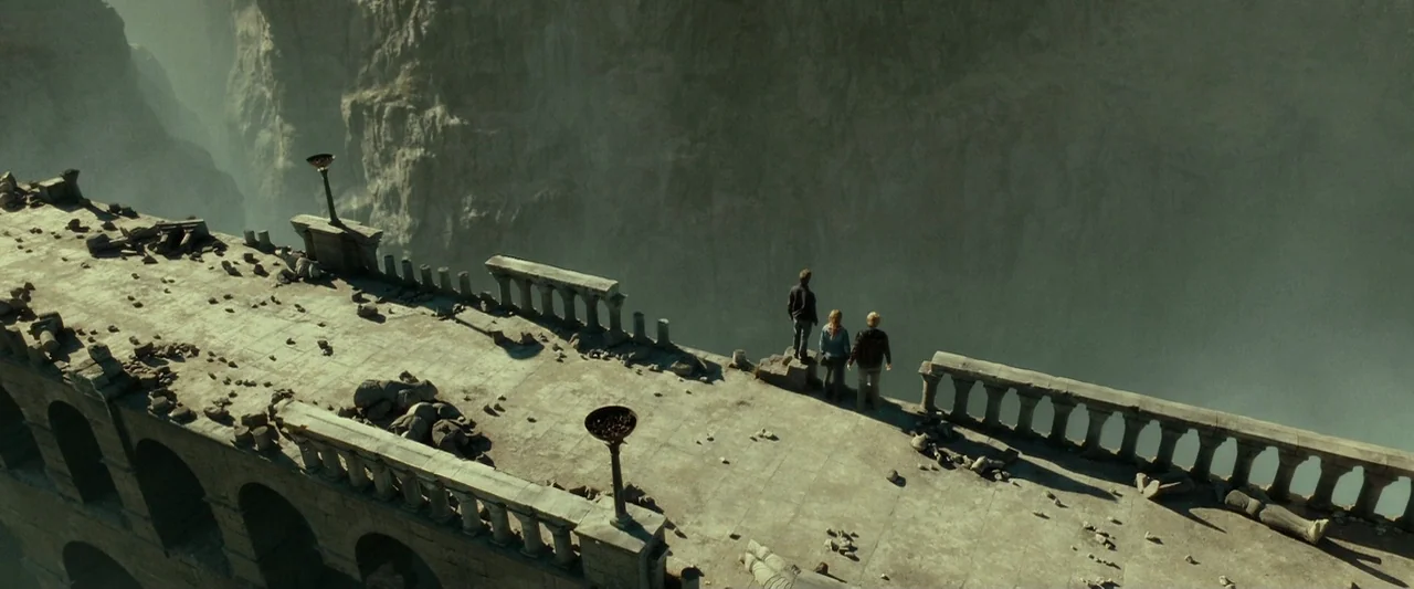 Harry Potter & The Deathly Hallows Part 2 (2011) movie still: wide — A long, weathered stone bridge with crumbling balustrades overlooks a deep,…