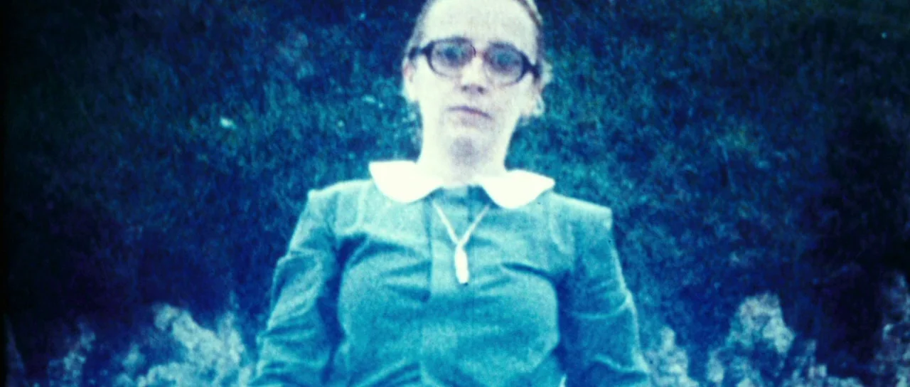 The Orphanage (2007) movie still: medium — A woman stands in a grassy field on a bright day. She looks directly at the camera while wearing a…