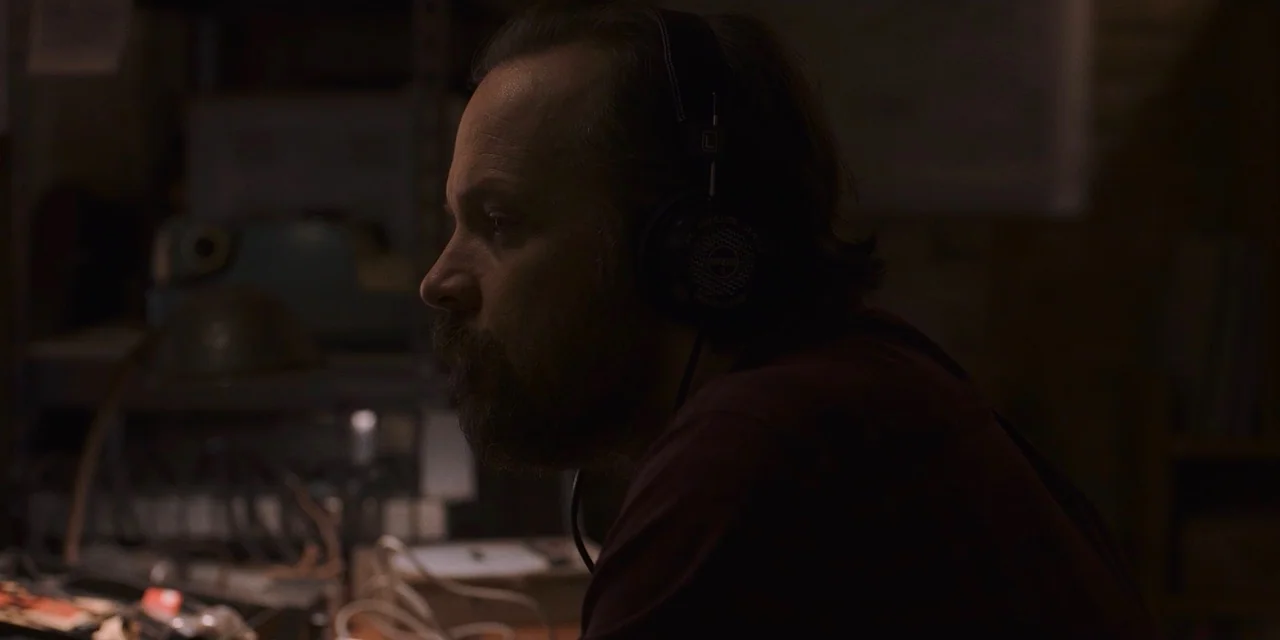 The Sound of Silence movie still: medium — A dimly lit room containing electronic audio equipment and tangled cables in the foreground. A…