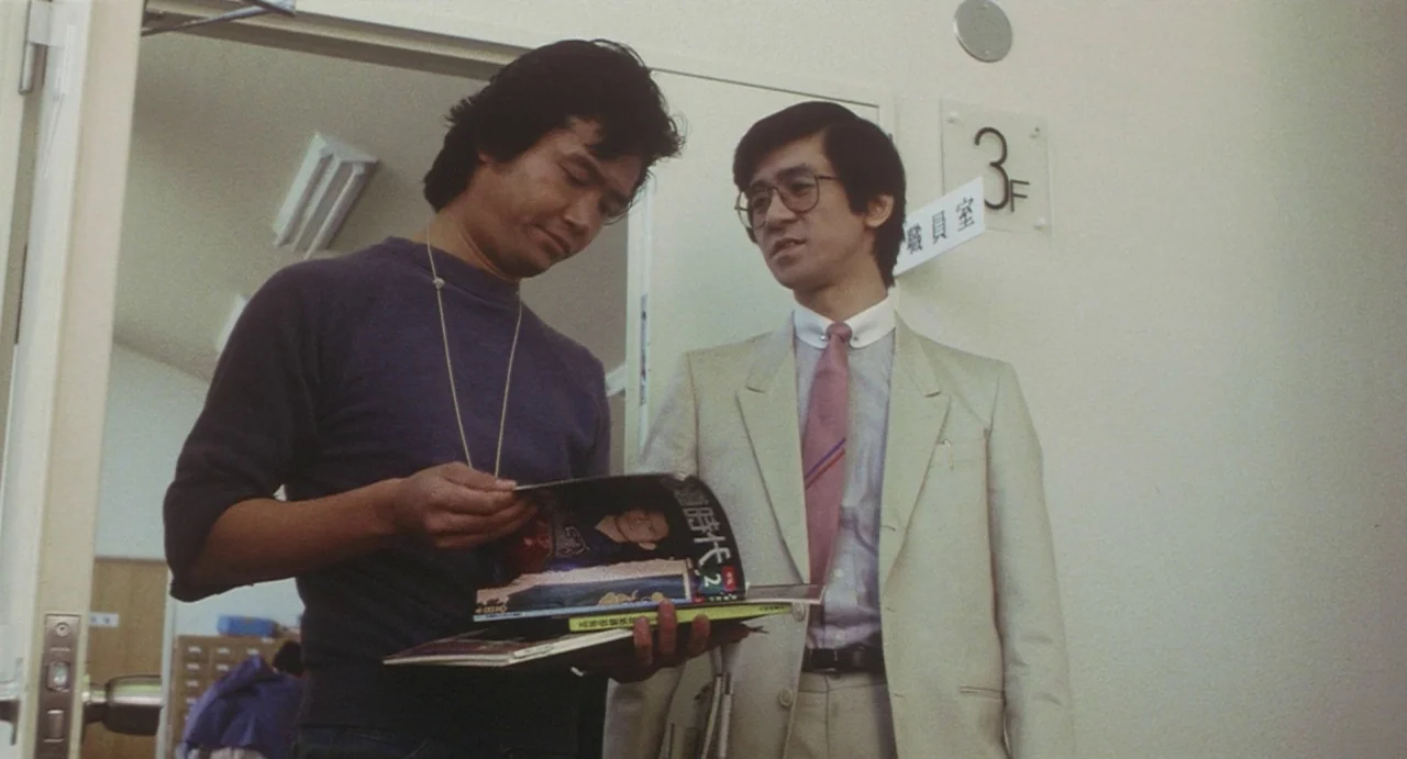School in the Crosshairs (1981) movie still: medium — A plain interior corridor features beige walls and a sign indicating a third floor. Two men…