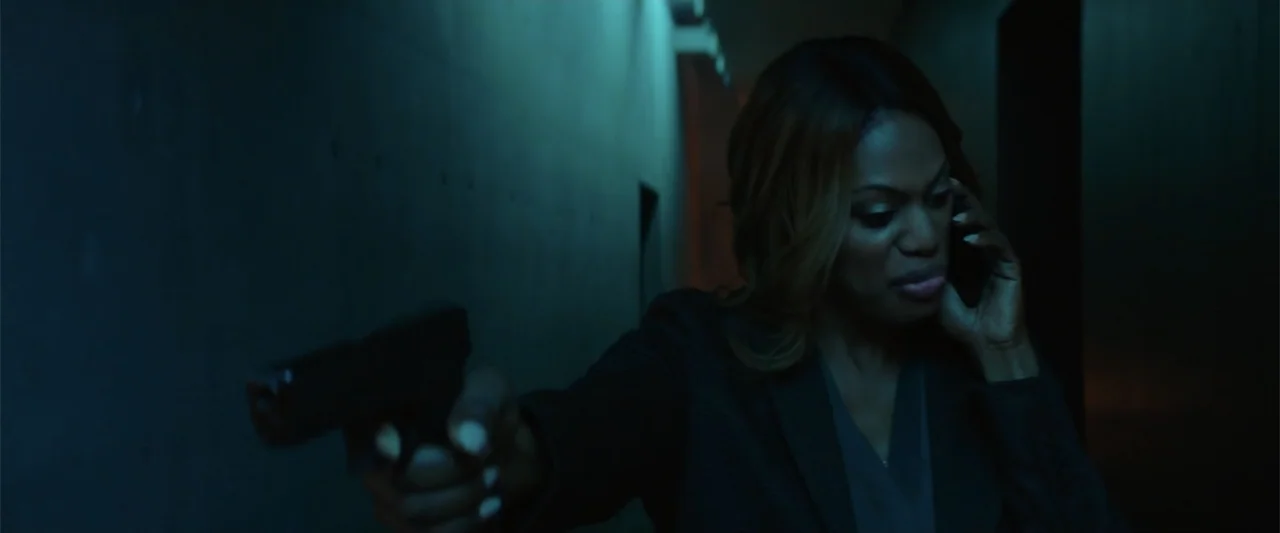 Jolt (2021) movie still: medium — A dark, dimly lit concrete corridor features walls with subtle textural details. A woman stands in the shadows…