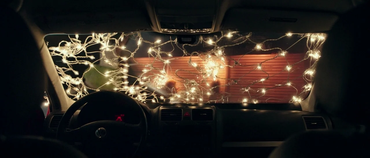 The Purge: Election Year (2016) movie still: medium — The interior of a Volkswagen car viewed from the back seat at night. Strings of white fairy…