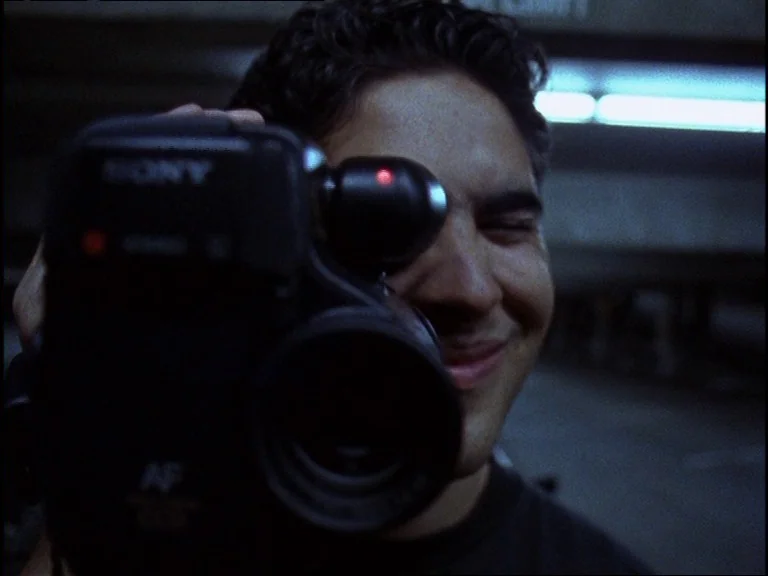 Totally F***ed Up (1993) movie still: closeup — A dimly lit parking garage with distant fluorescent lights visible in the background. A young man…