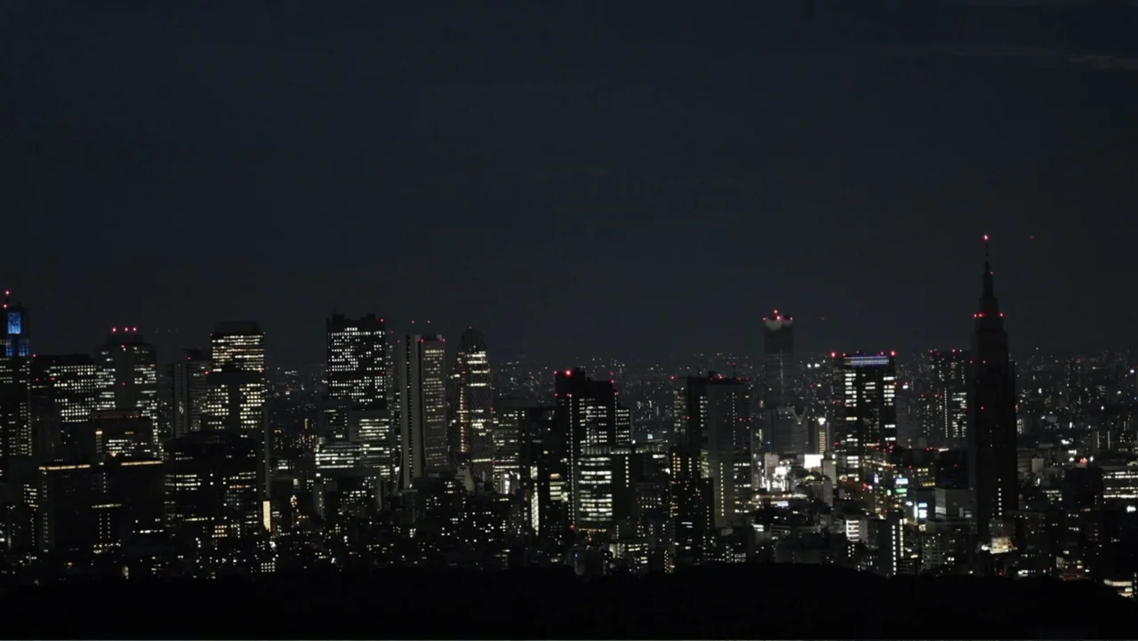 Vai Corinthians (2023) movie still: establishing — A dense urban metropolitan skyline spans the horizon at night under a dark sky. Countless…