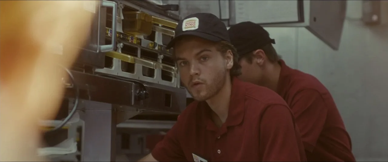 Into the Wild (2007) movie still: medium — A professional food preparation area with stainless steel equipment and shelves. A young man wearing a…