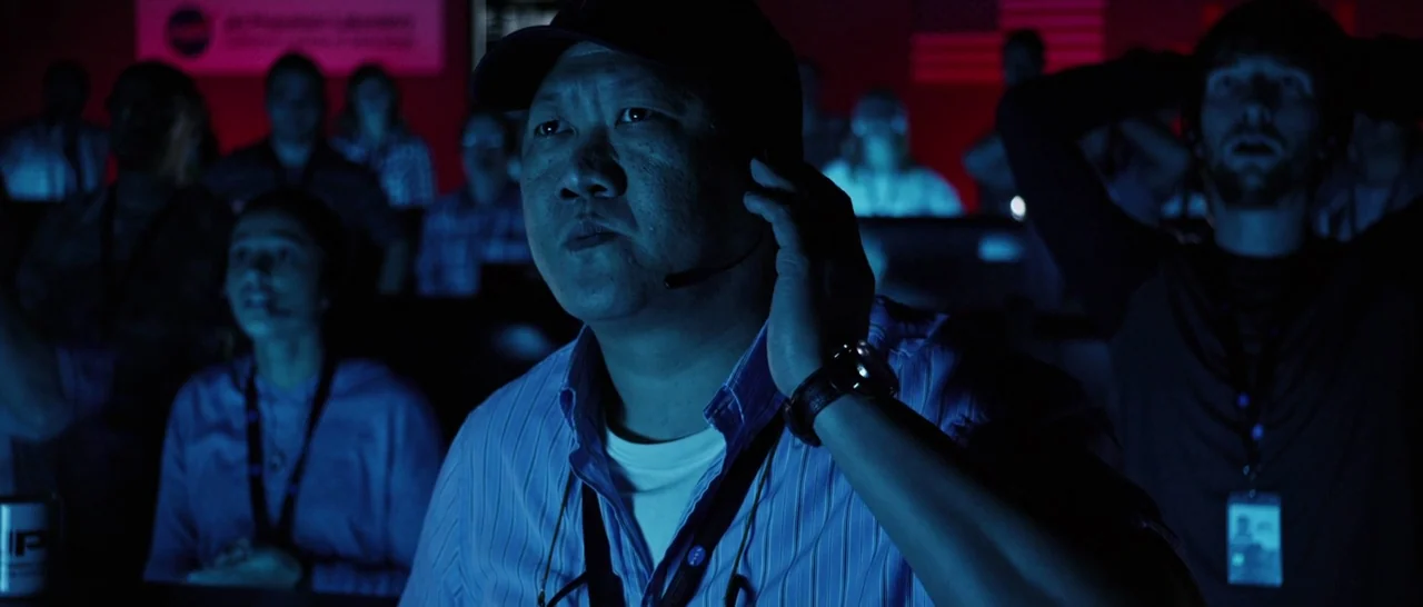 The Martian (2015) movie still: medium — A crowded mission control center with workers sitting at stations behind the central subject. A middle-aged…