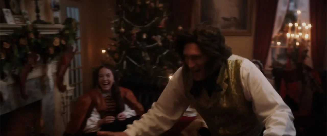 I Heard the Bells (2022) movie still: medium — A dimly lit Victorian drawing room is decorated with a large Christmas tree and greenery. A man in a…