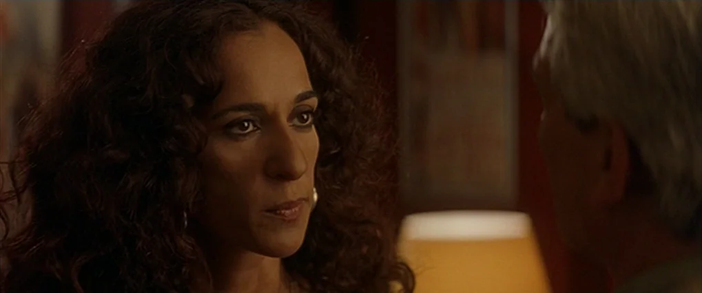 Talk To Her (2002) movie still: closeup — A dark, dimly lit room contains a person seen in a close-up shot. The woman faces toward the right side of…