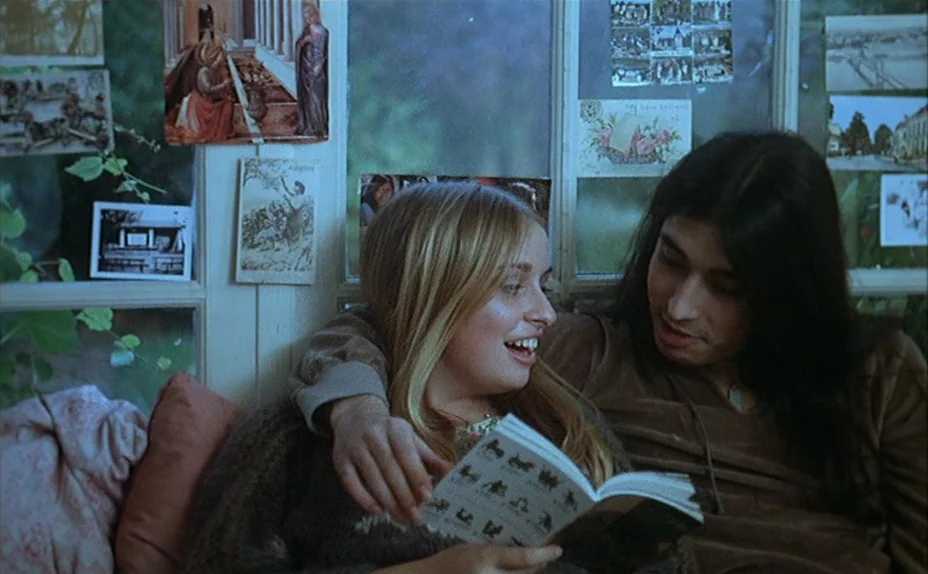 L’une Chante, l’Autre Pas (1977) movie still: medium — An interior alcove features large windows adorned with numerous vintage postcards and printed…