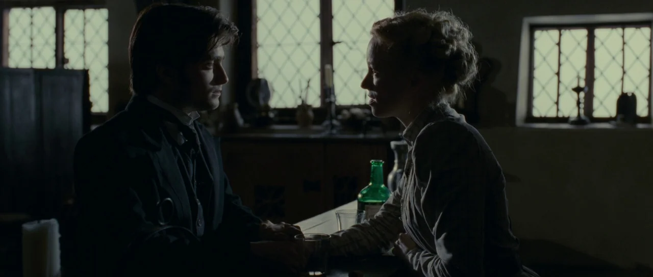 The Woman in Black (2012) movie still: medium — A dimly lit 19th-century room features diamond-paned windows casting bright light against a dark…