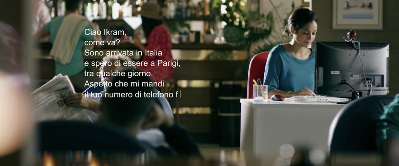 Taranta On the Road (2017) movie still: medium — An internet cafe features patrons using computers with blurred background shelves and bar seating.…