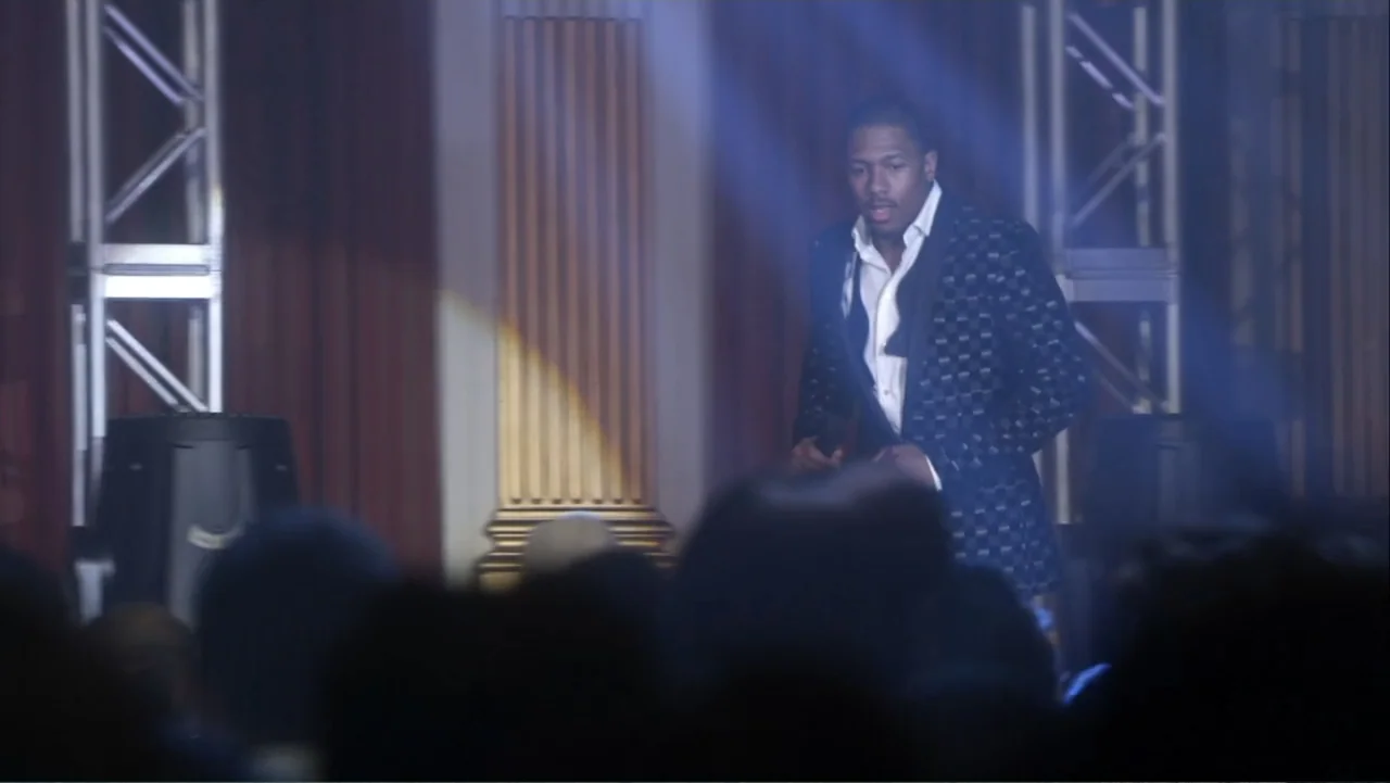 Rags (2012) movie still: medium — A stage set with metallic truss structures and gold fluted pillars in the background. A man in a dark patterned…