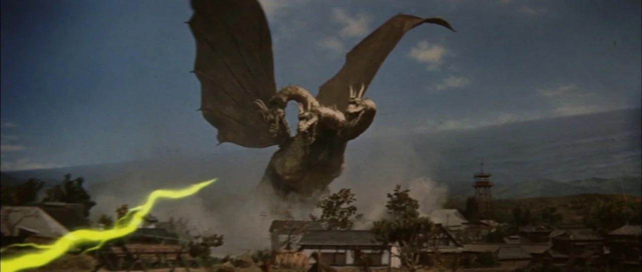 Ghidorah The Three Headed Monster (1964) movie still: wide — A miniature rural Japanese village sits below a massive golden three-headed dragon. The…