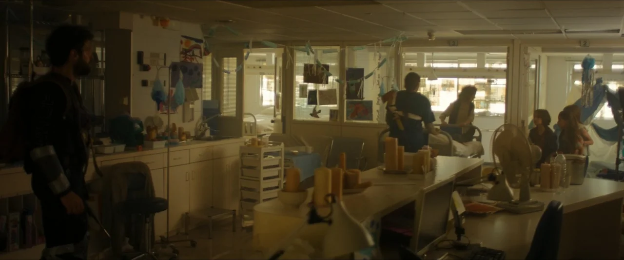 Apocalypse Z: The Beginning of the End (2024) movie still: wide — A cluttered hospital room contains medical stations, desks, and children's…