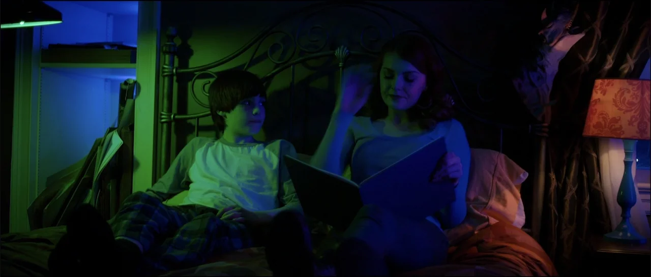 Halloween III: Season of the Witch (1982) movie still: medium — A dark room features a bed with an ornate metal headboard at night. A woman reads…
