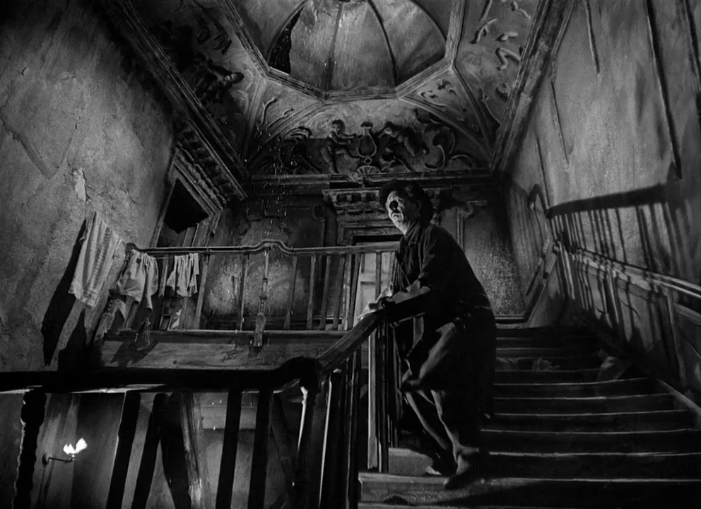 Odd Man Out (1947) movie still: wide — An old, dilapidated interior staircase features crumbling plaster walls and decorative vaulted ceiling relief…