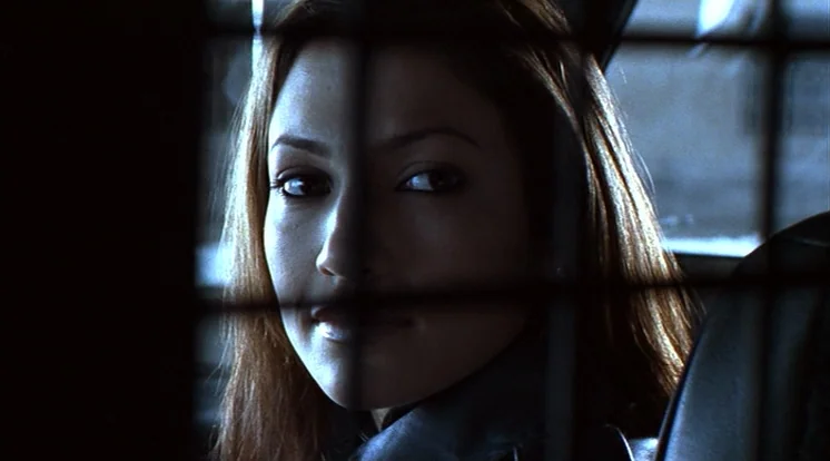 Out Of Sight (1998) movie still: closeup — The interior of a vehicle with a black wire partition separating the front seat. A woman sits in the back…