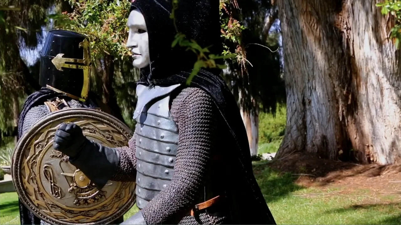 Empire Queen: The Golden Age of Magic (2024) movie still: medium — A sunny outdoor park features large trees and green grass in the background. Two…