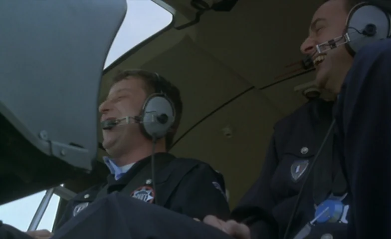 I Can’t Sleep (1994) movie still: medium — The interior of a helicopter cockpit features two men in navy blue uniforms. Both men wear headsets and…