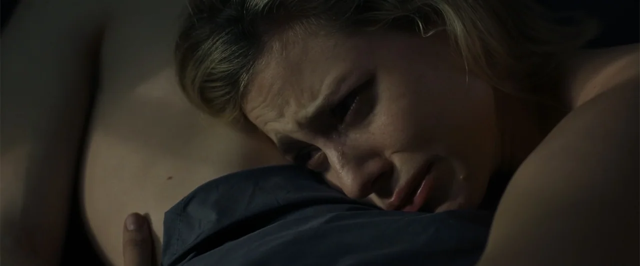 Chemical Hearts (2020) movie still: closeup — A dark bedroom interior with the focus placed on a woman's face and shoulder. A woman rests her head…