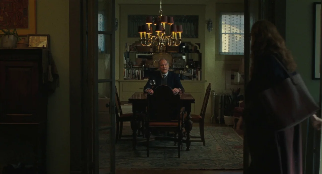 When You Finish Saving The World (2022) movie still: wide — A traditional room features a wooden dining table and a low-hanging ornate chandelier.…