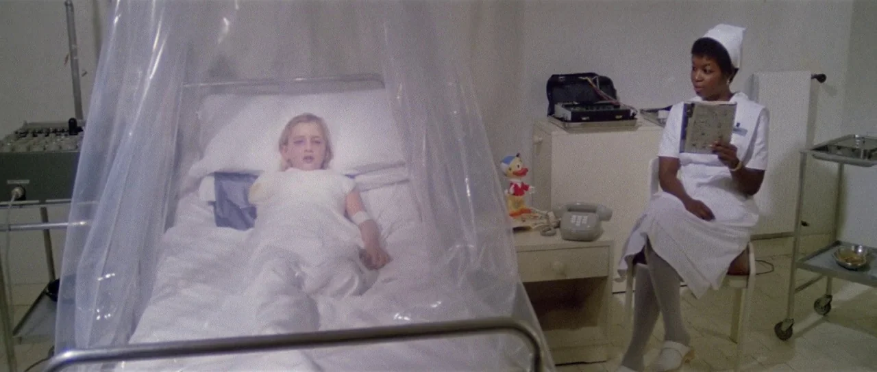 The New York Ripper (1982) movie still: wide — A medical isolation room contains a transparent plastic tent covering a child's hospital bed. A nurse…
