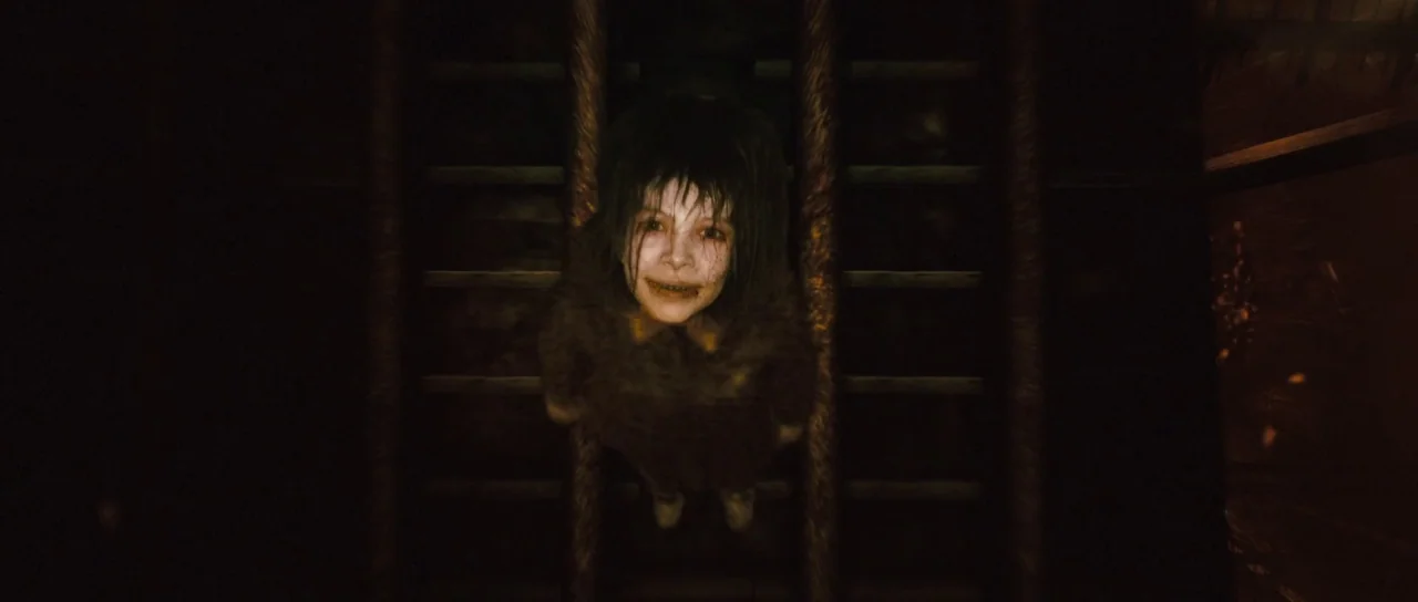 Silent Hill movie still: medium — A dark wooden staircase interior shrouded in deep shadows. A young child stares upward toward the camera from the…