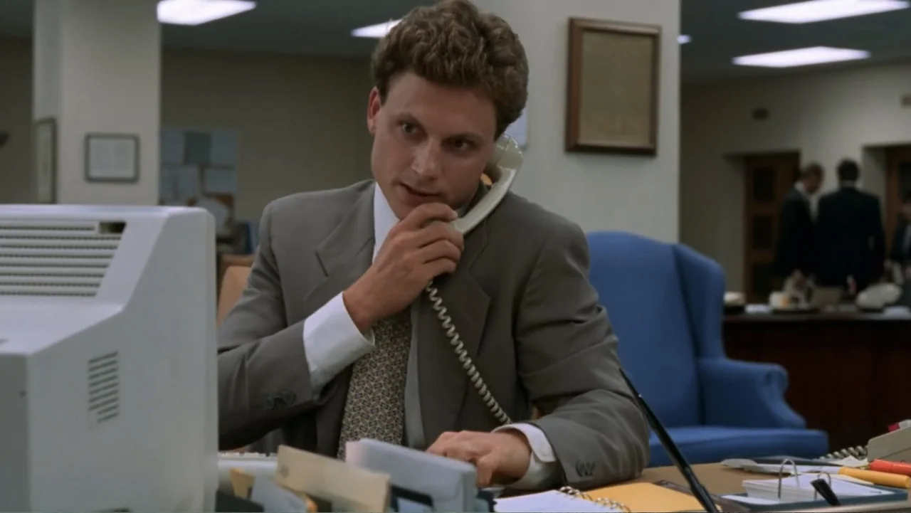 Ghost (1990) movie still: medium — An office interior features beige walls, blue furniture, and white computer equipment on desks. A man in a suit…