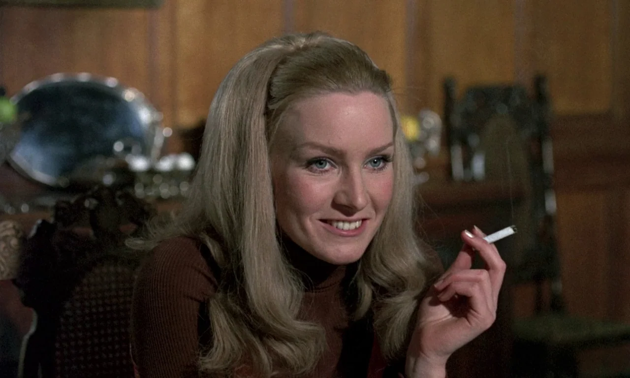 Curse of the Crimson Altar (1968) movie still: closeup — A wood-paneled room serves as the backdrop with an out of focus silver platter. A woman…