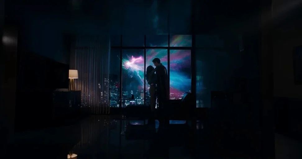 Superman (2025) movie still: wide — A darkened, minimalist high-rise apartment interior overlooks a city at night. A couple stands in silhouette…