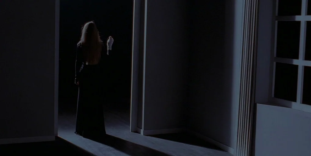 Dominion: Prequel to the Exorcist (2005) movie still: fullbody — A dimly lit room connects to a pitch-black space through an open doorway. A blonde…