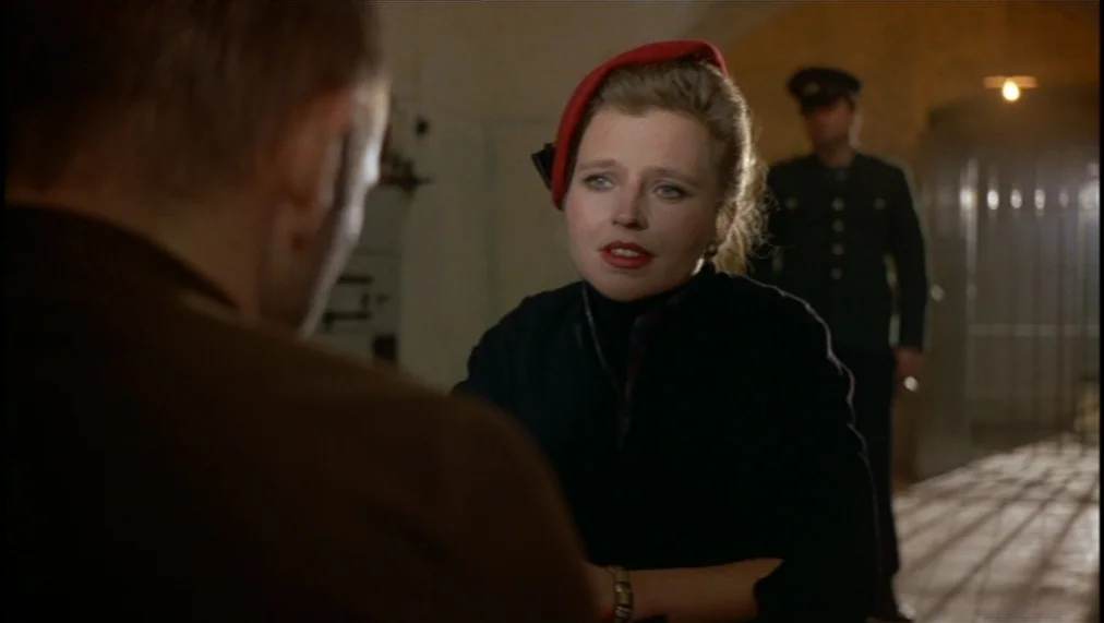 The Marriage of Maria Braun (1979) movie still: medium — A dimly lit room with iron bars and stone walls reflects an austere environment. A woman…