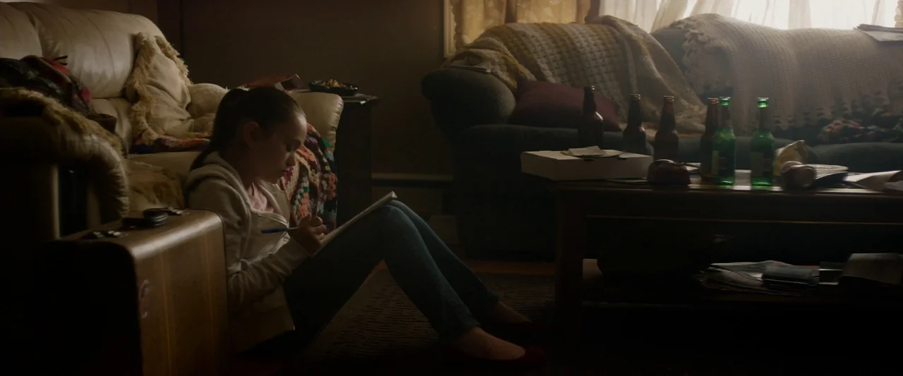The Monster (2016) movie still: medium — A cluttered living room features two sofas, a wooden coffee table, and discarded beer bottles. A young girl…