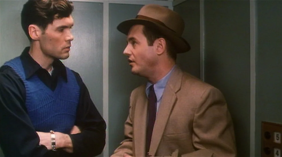 Union City (1980) movie still: medium — Two men stand closely inside a small, panelled space with a numbered floor indicator. The man in the hat…