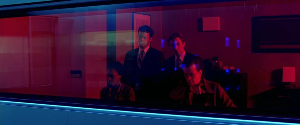 The Cell (2000) movie still: medium — Four individuals gather inside a darkened room separated by a pane of glass. They watch an event occurring on…