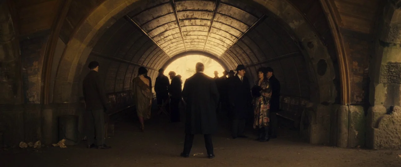 The Immigrant (2013) movie still: wide — A group of figures in 1920s period clothing stand inside a dark stone tunnel. They are silhouetted against…