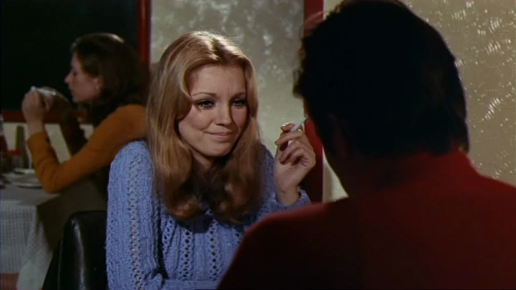 The Sorcerers (1967) movie still: medium — A diner booth with textured glass partitions separates patrons in a dimly lit space. A woman in a blue…