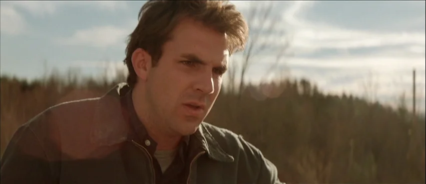 All The Real Girls (2003) movie still: medium — An open landscape with blurred trees in the distance stands behind a single man. The man looks…
