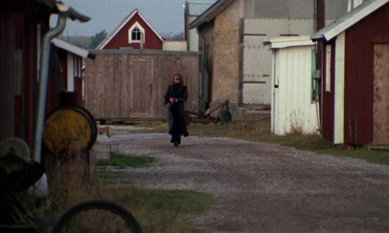 Thriller: A Cruel Picture (1973) movie still: wide — A rural farm courtyard with several wooden sheds and storage buildings of varying colors. A…