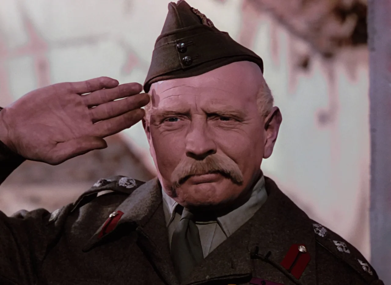 The Life and Death of Colonel Blimp (1943) movie still: closeup — A soldier stands before a blurred background of dirt and ruined masonry walls. An…