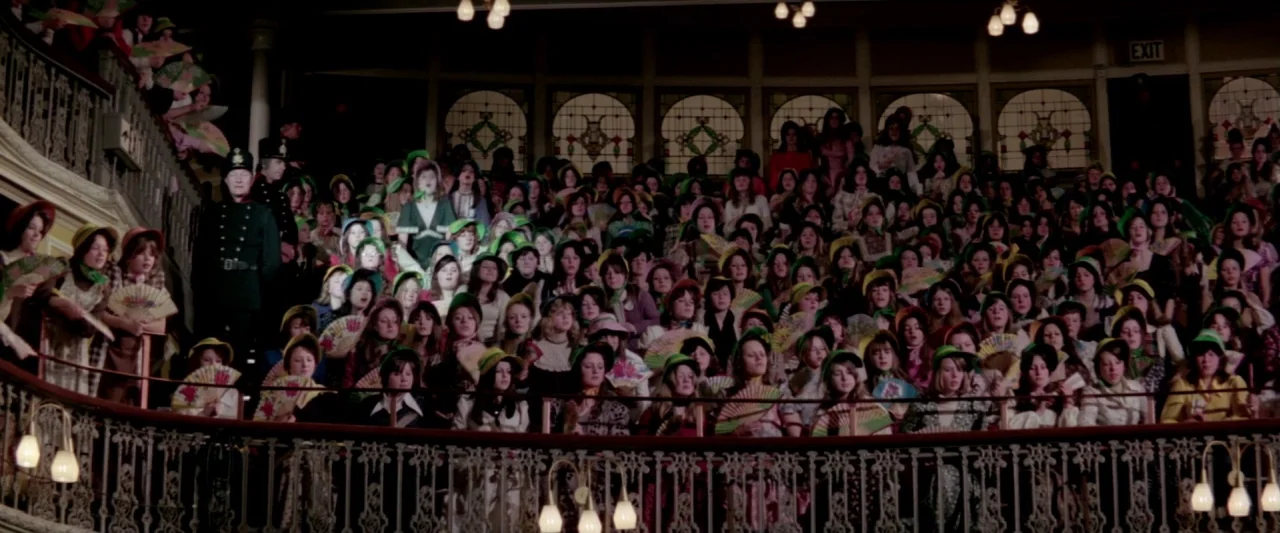 Lisztomania (1975) movie still: wide — A dense, crowded theater balcony filled with women holding decorative hand fans. The venue features ornate…