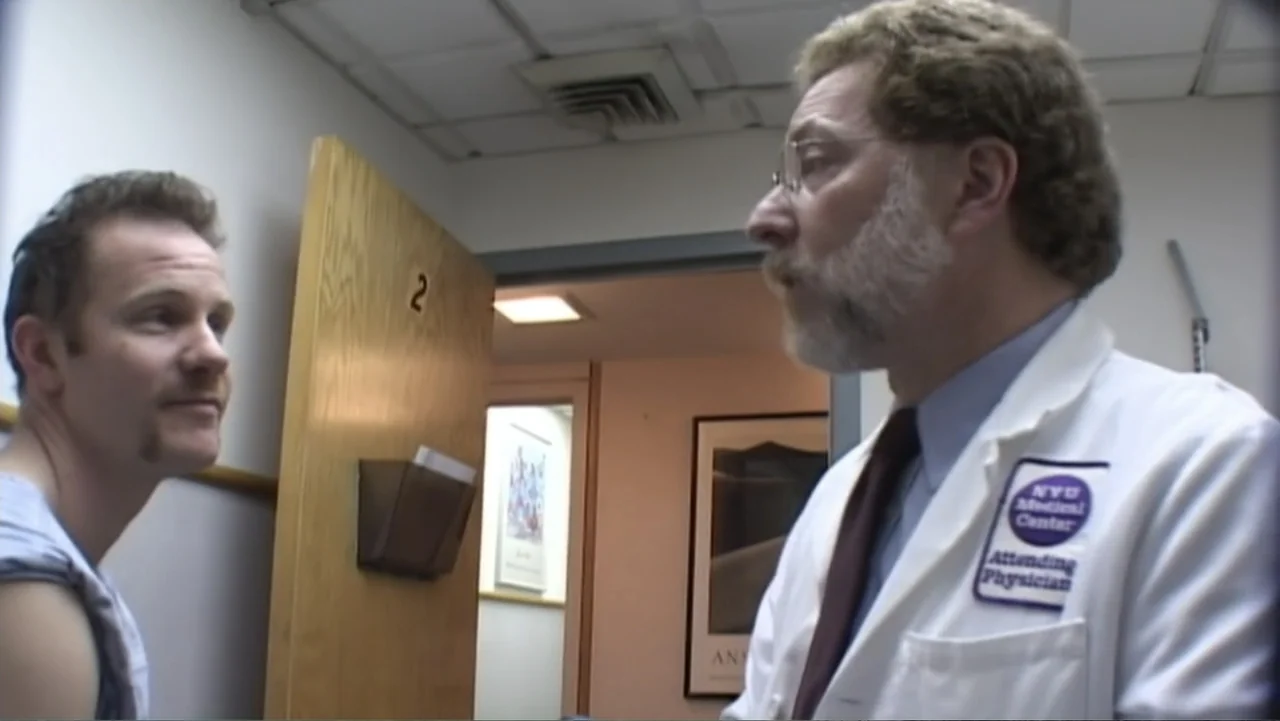 Super Size Me (2004) movie still: medium — A clinical examination room with beige walls and a wood-veneer door numbered two. An older male doctor in…