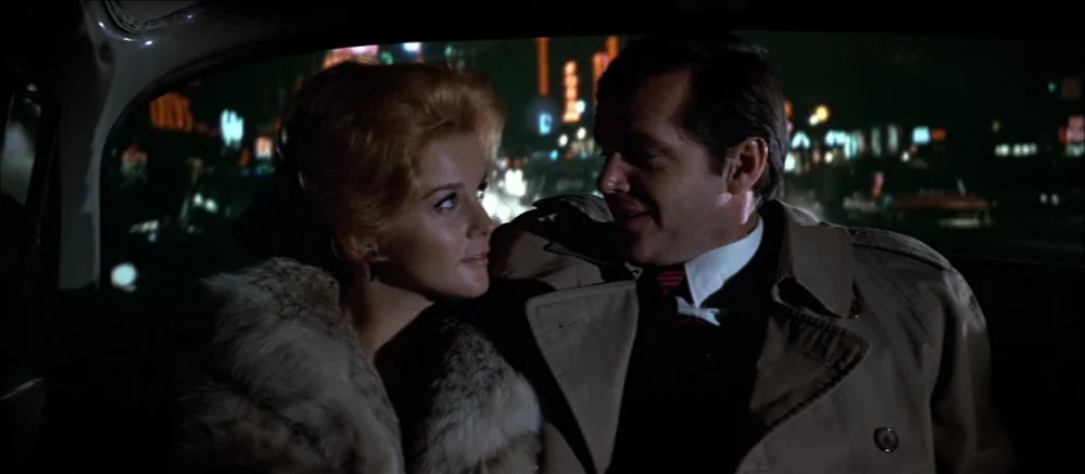 Carnal Knowledge (1971) movie still: medium — The interior of a moving vehicle at night with a blurred city skyline visible. A man and a woman sit…