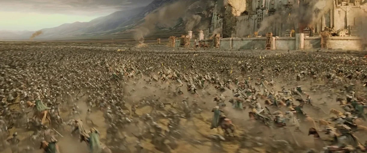 A vast, dusty battlefield stretches before a large stone fortress built into a mountain. Thousands of armored horse-mounted warriors charge across the field in a massive confrontation.