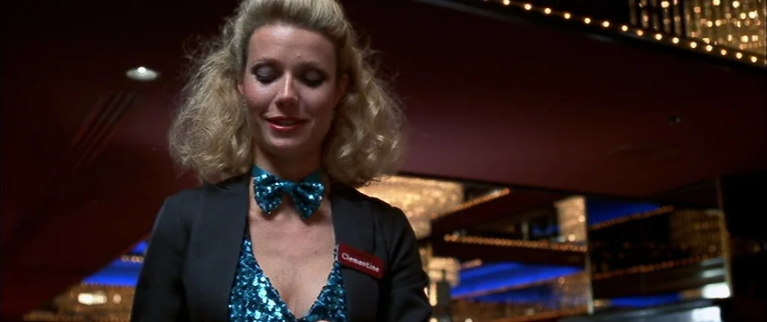 Hard Eight (1996) movie still: medium — A woman stands in a dimly lit casino space with glittering decorative ceiling lights. She is wearing a…