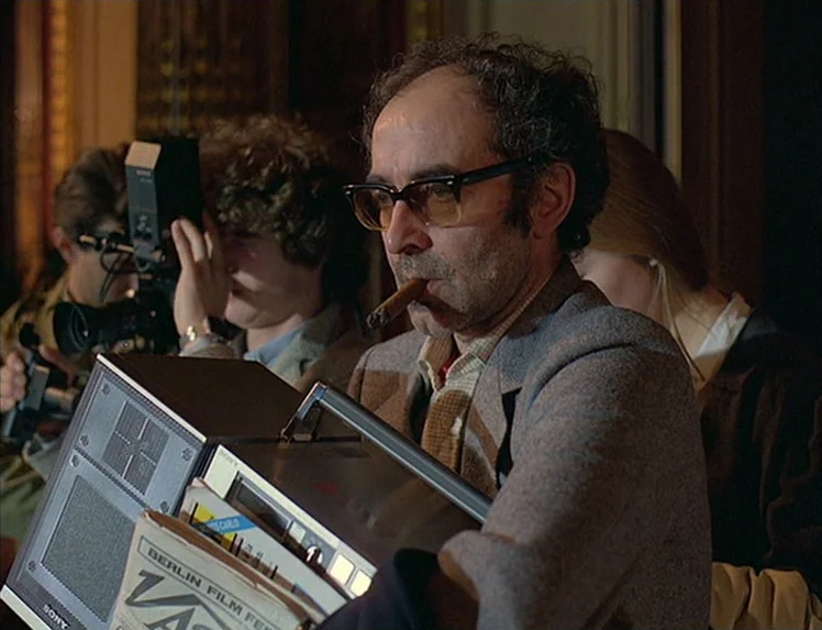 First Name: Carmen (1983) movie still: medium — A crowded professional setting with journalists and technical equipment visible in the background. A…