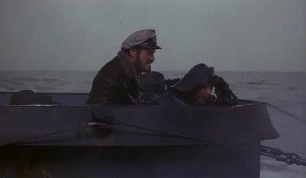 Das Boot (1981) movie still: medium — A metal conning tower sits atop a submarine amidst a vast, choppy gray ocean. Two men in uniform look outward…