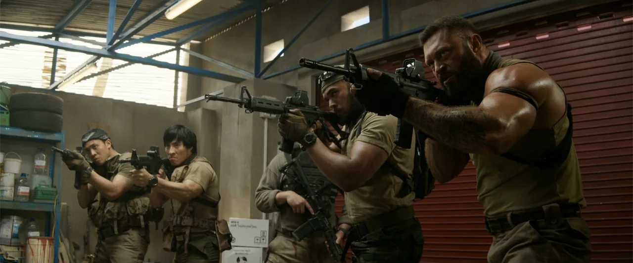 Meg 2: The Trench (2023) movie still: medium — A utilitarian industrial space features concrete walls and red metal roll-up doors.