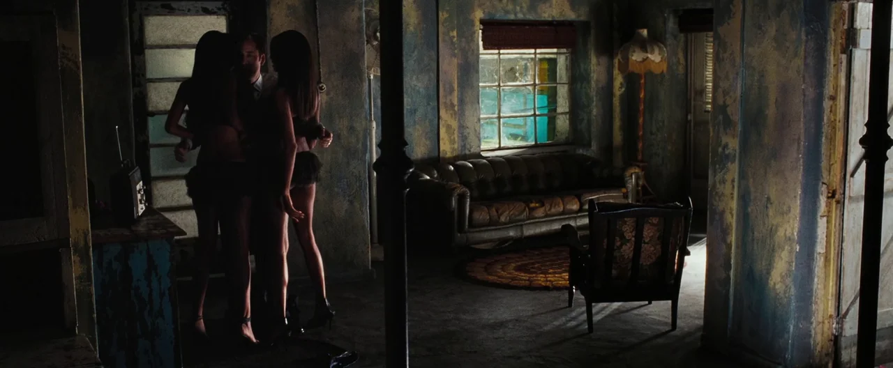 Lord of War (2005) movie still: wide — A dark apartment interior features crumbling walls with patches of peeling paint and texture. A man stands…