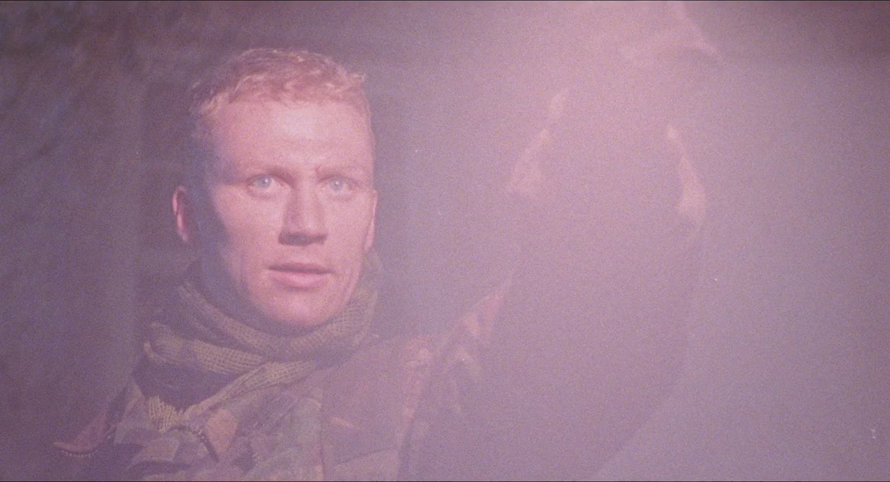Dog Soldiers (2002) movie still: closeup — A dense, dimly lit jungle environment filled with thick, low-hanging atmospheric mist or smoke. A soldier…